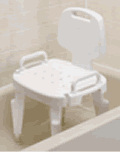 A white, plastic chair with arms and a backrest sitting in a bathtub. The seat has holes for water drainage and is about the same height as the bathtub edge.