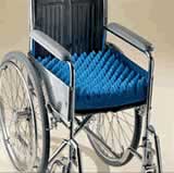 A wheelchair with an egg crate-style, Styrofoam cushion on the seat.