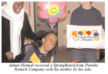 Photo of Adnan Hemedi receiving a SpringBoard from Prentke Romich Company with his mother by his side.