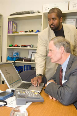 Photo of Marvin Williams (standing), an assistive technology specialist at the center, shows Sen. Carper how some of the devices work.