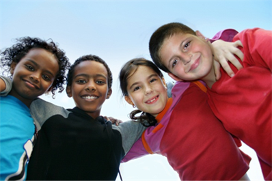 Title: A photo used for Inclusion Conference marketing. - Description: The photo is of four school-aged children, arm-in-arm, standing in a semi-circle, smiling while looking down at the camera.
